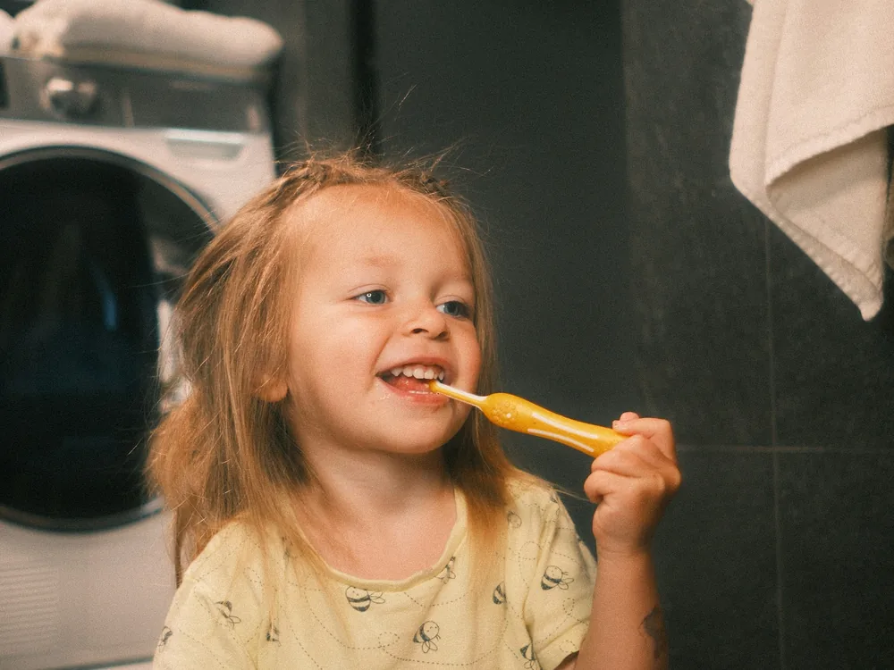 Criança sorrindo enquanto escova os dentes